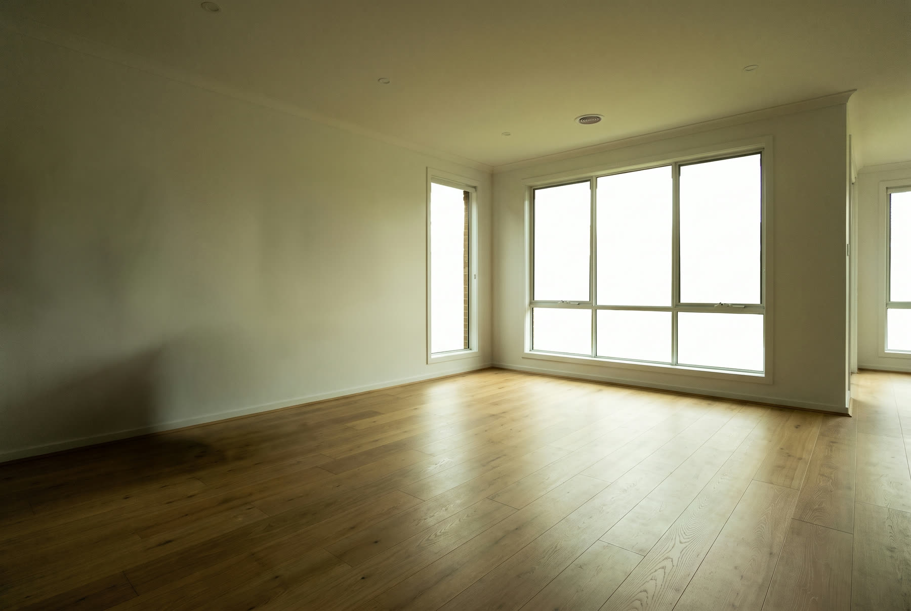 The same empty living room as an unedited phone photo, dim and slightly tilted.